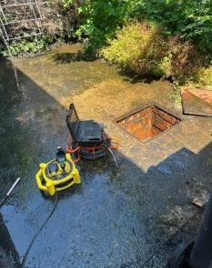 Flooded garden drain being cleared with a jetter