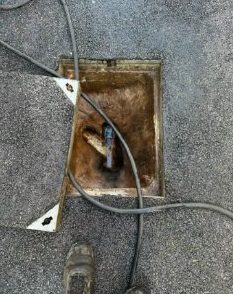 Rods going into a blocked manhole on a driveway